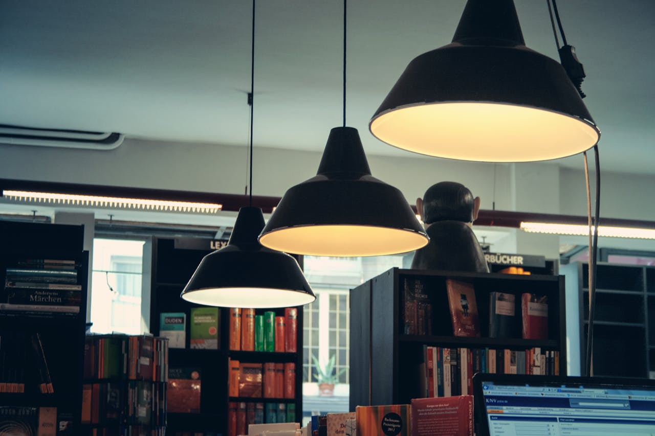 A welcoming bookstore interior with hanging lamps illuminating the shelves filled with books.