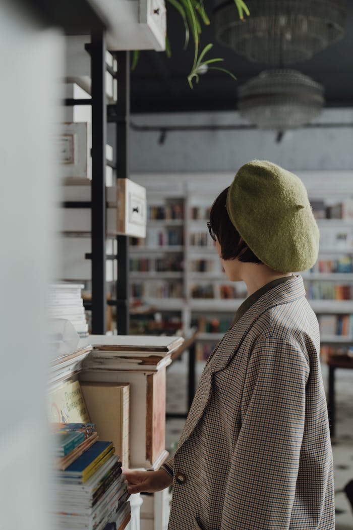 A woman in a beret and checked coat explores a cozy bookstore filled with bookshelves and literature.